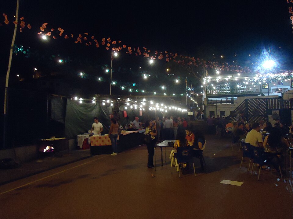 Night arraial in Santo António, Funchal — strings of lights, paper garlands and an espetada fire