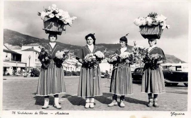 Four Madeiran flower sellers in striped skirts with flower baskets on their heads, photo postcard c.1940